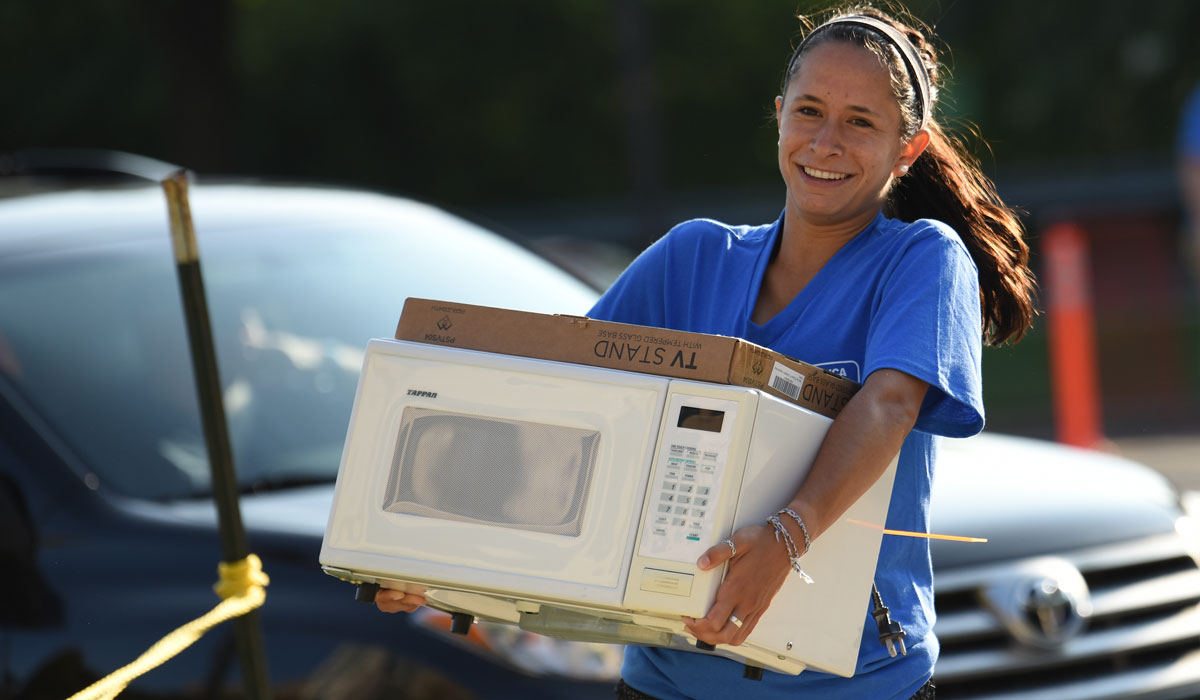 Female student carrying a microwave