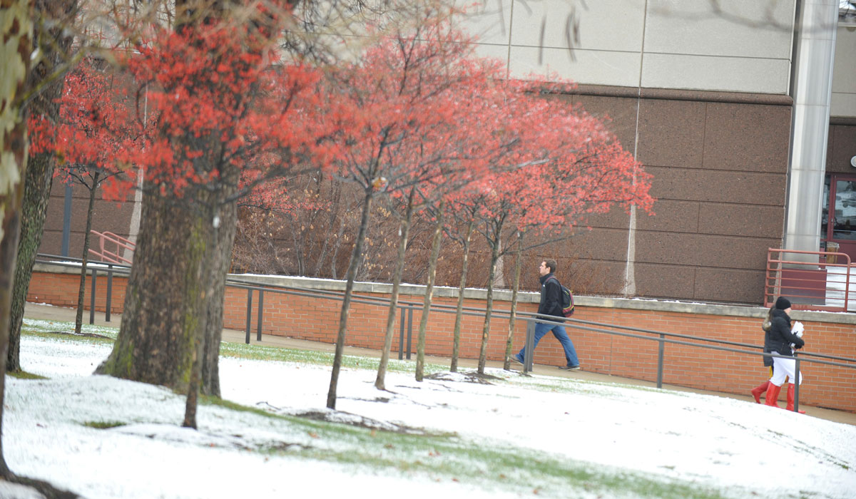 Student walking across campus with snow on the ground